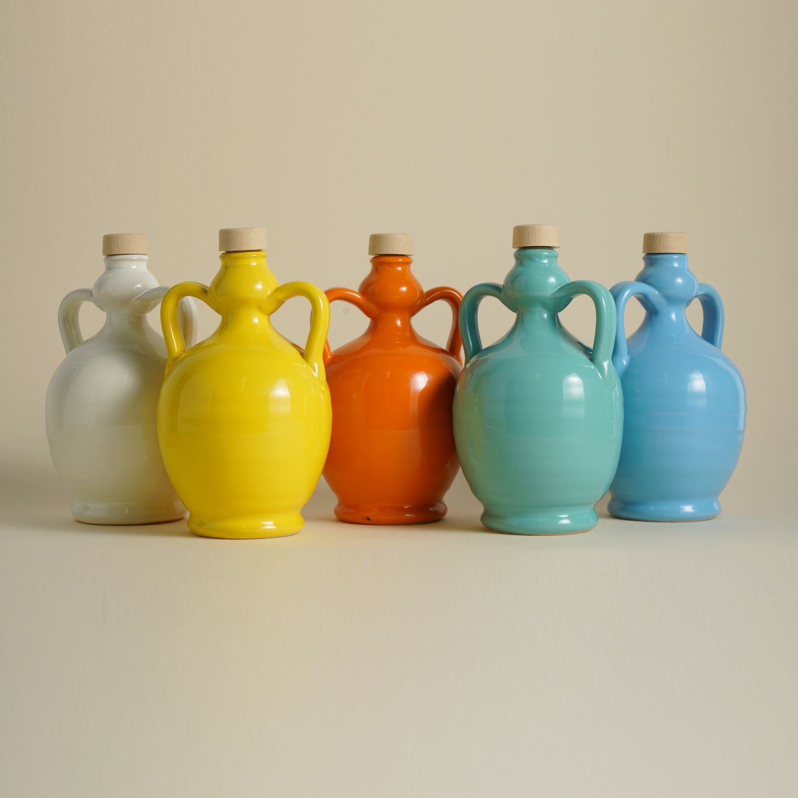 Bottiglie colorate in ceramica per Olio Extravergine di Oliva con tappo in legno elegantemente disposte