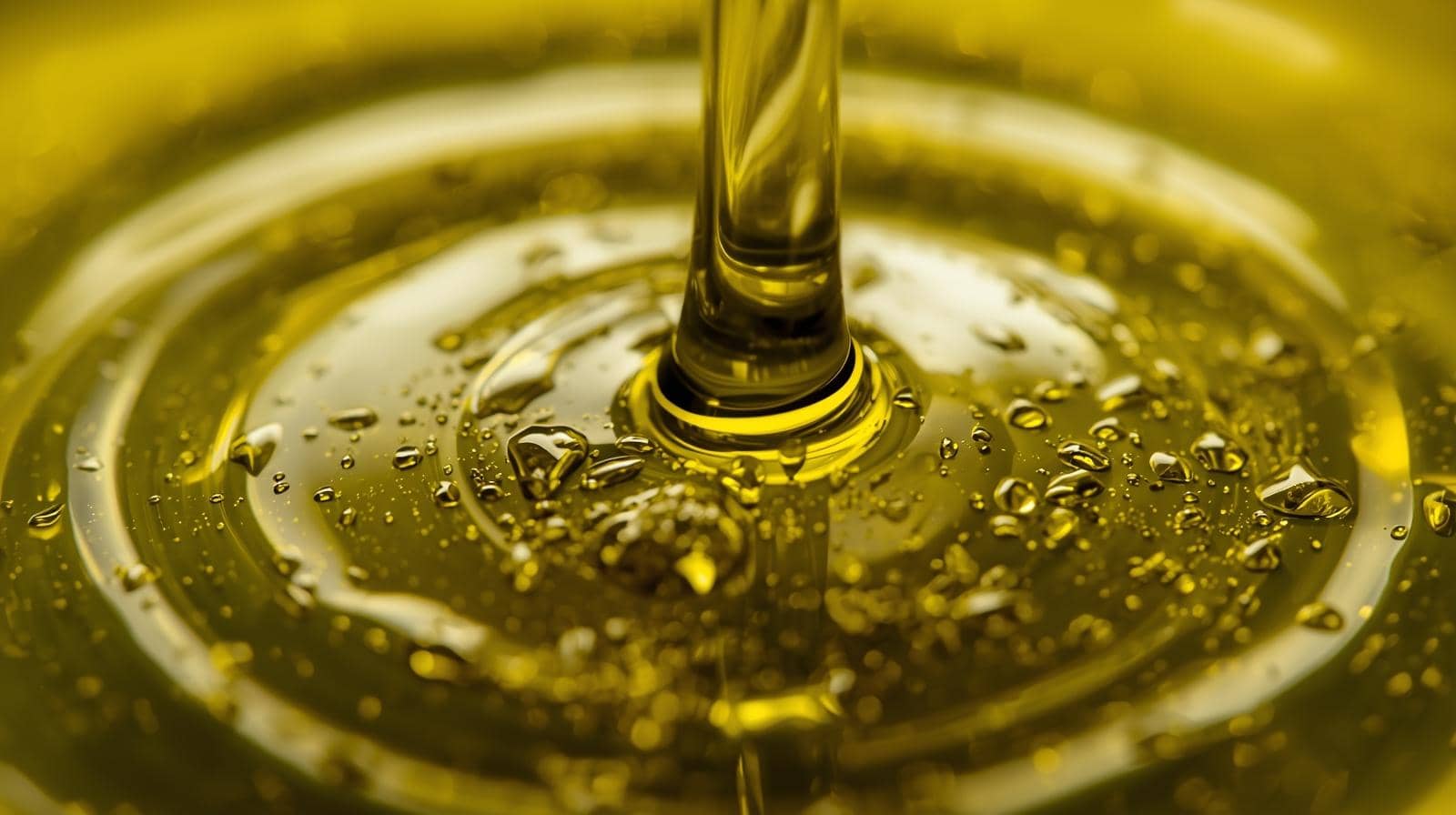 Olio Extravergine di Oliva versato in una ciotola con riflessi dorati e bolle di aria